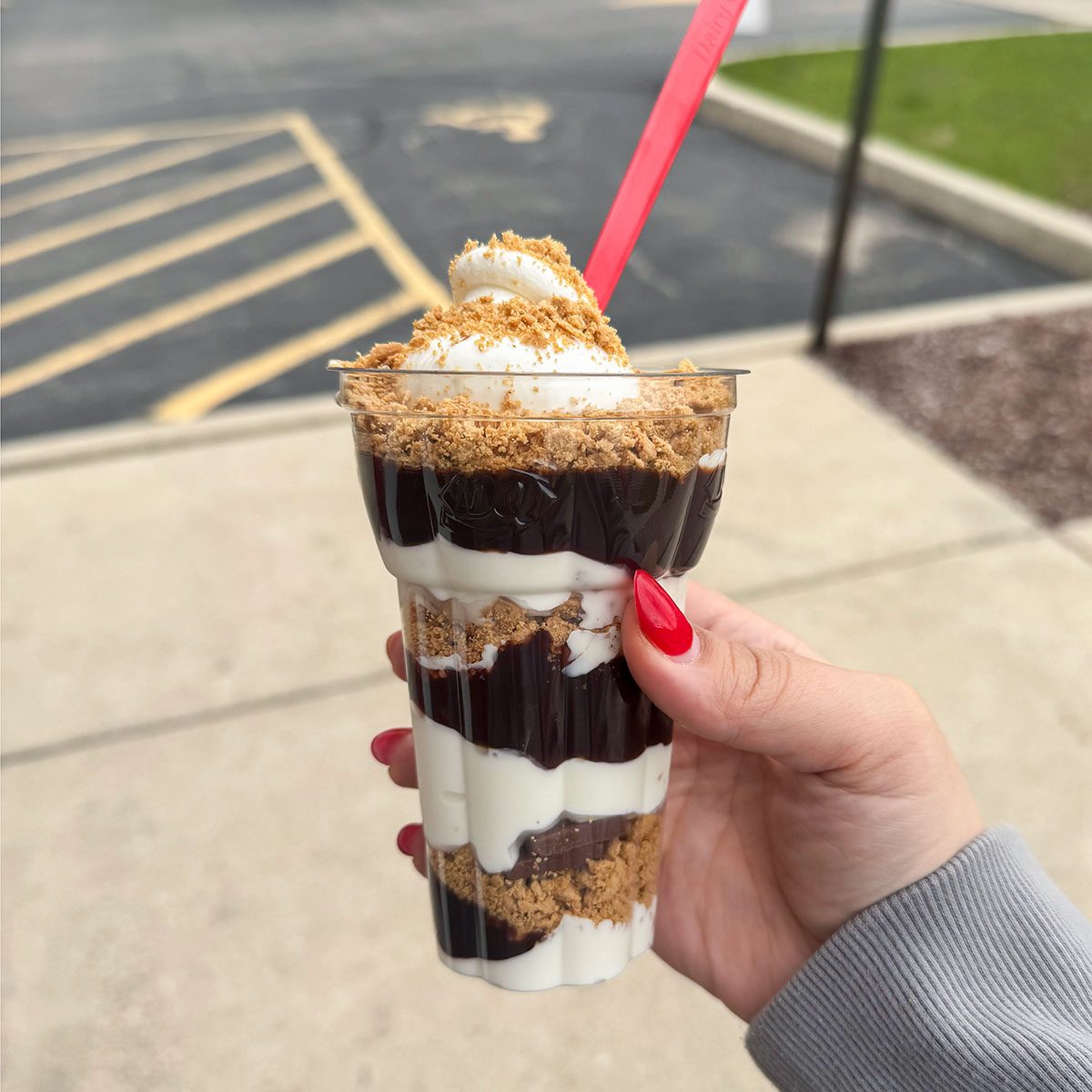 A closeup of hand holding S'more Galore Parfait