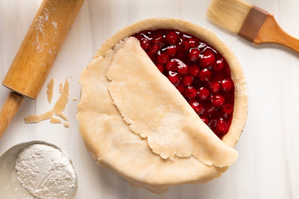 A pie with cherries and a rolling pin