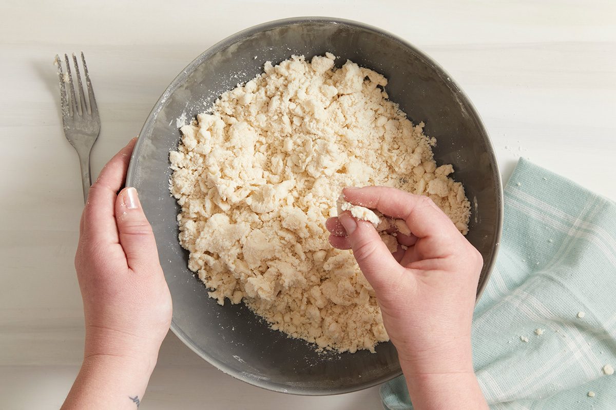 Overhead shot of tossing with a fork until dough holds together when pressed; fork; a napkin; on cream surface