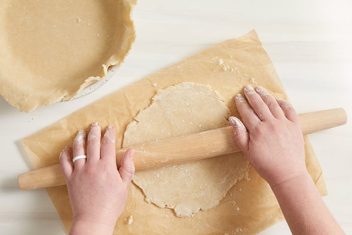 Overhead shot; On a lightly floured surface roll out half of dough to a 1/8-inch thick circle; transfer to a 9-inch or 10-inch pie plate; Trim even with rim; cream surface