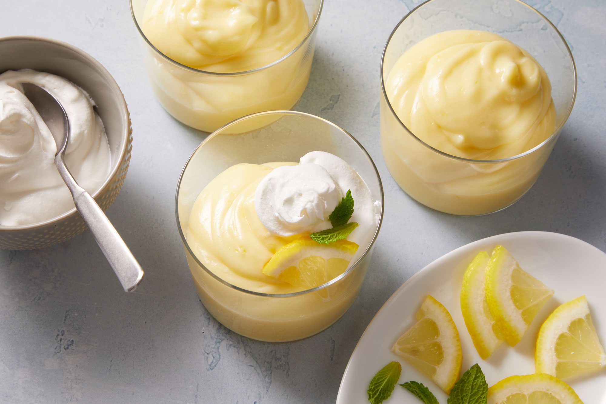 High angle shot of Lemon Pudding topped with whipped cream, lemon slice and mint leaves