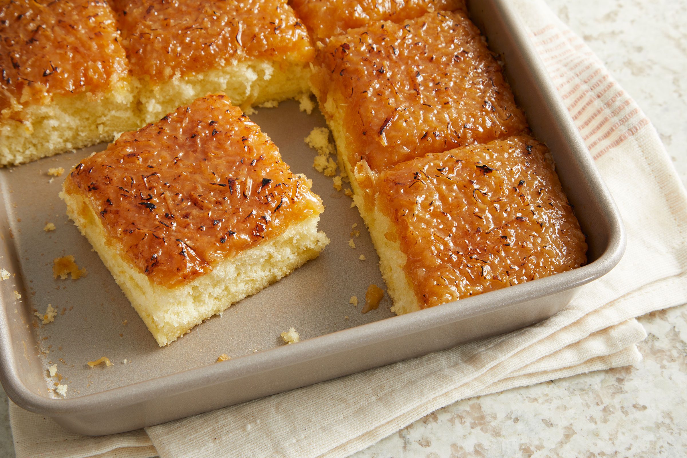 Square pieces of Moist Lazy Daisy in a square baking pan.
