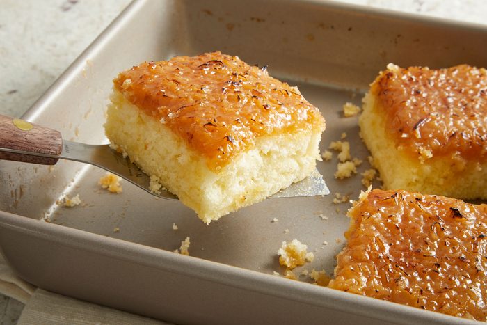 Lifting a square piece of Moist Lazy Daisy in a square baking pan.
