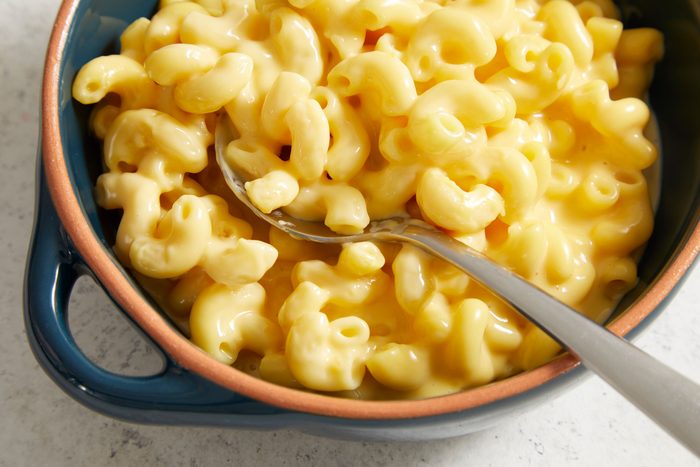 overhead closeup shot of a bowl of Potluck Macaroni and Cheese, a silver spoon is nestled among the pasta