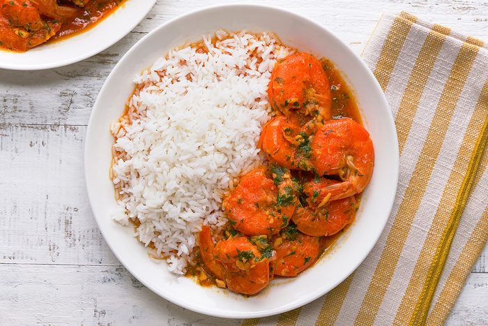 A plate featuring rice and shrimp accompanied by a side of rich curry sauce.