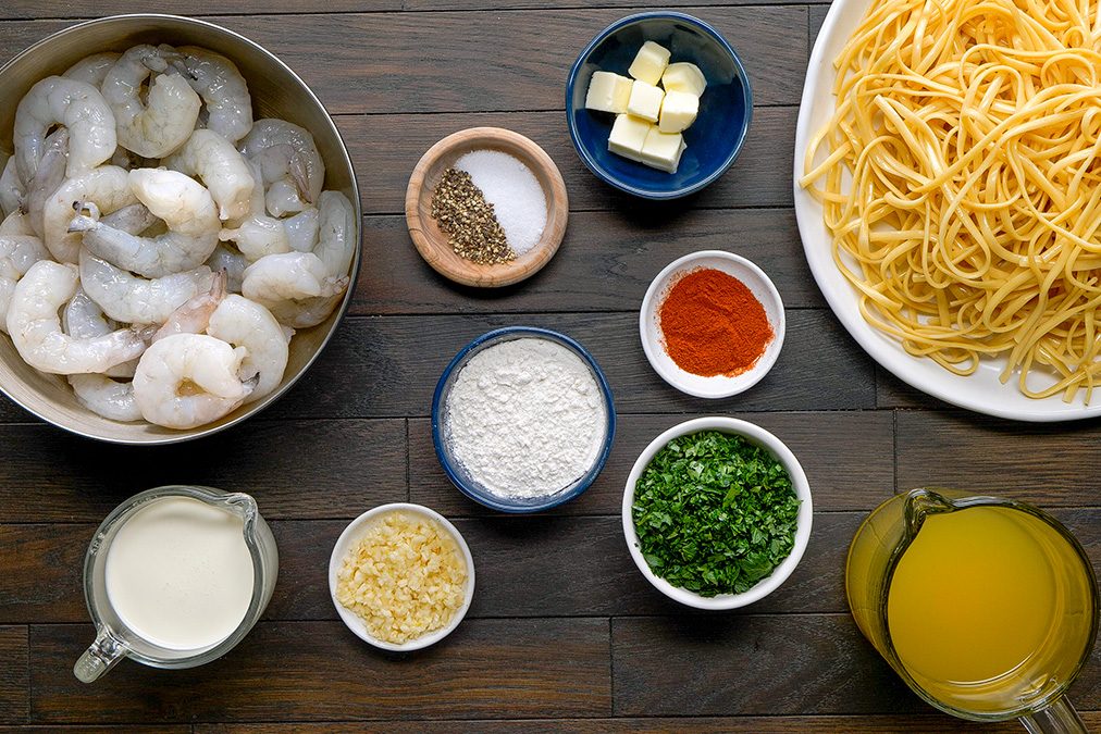 overhead shot of Shrimp in Cream Sauce ingredients placed over dark wooden background