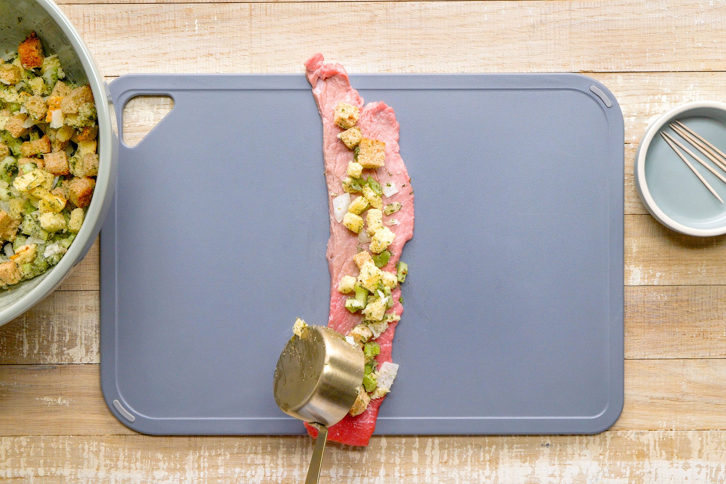 Rolling onion, butter, bread cubes, chopped celery and seasoning on a piece of steak.