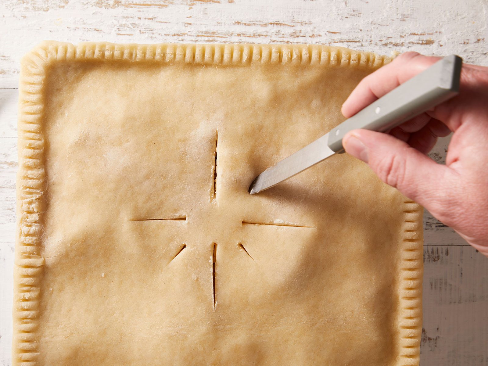 Cut slits in top of deep dish apple pie with paring knife