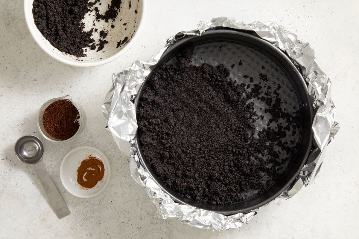In a small bowl, mix cookie crumbs and butter; press onto the bottom of prepared pan.