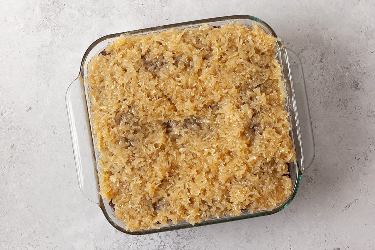 A glass baking dish filled with a baked casserole featuring a golden, crumbly topping, set on a light-colored surface.