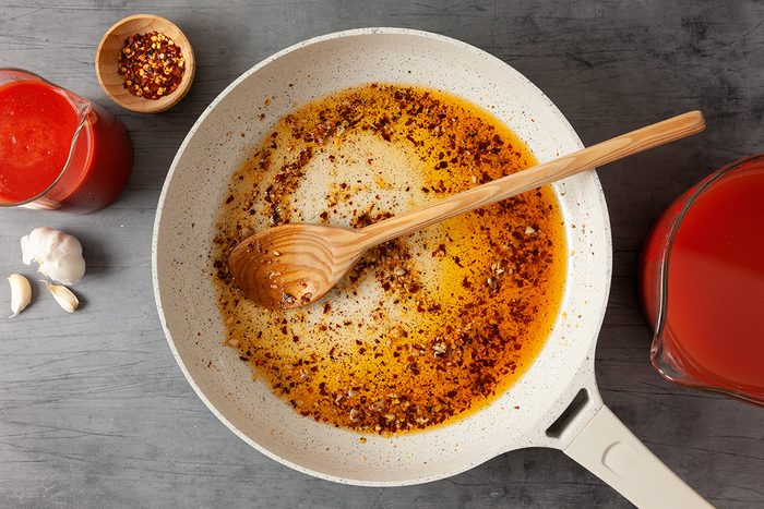 In a large heatproof container, stir together hot water, 1 cup passata sauce and tomato paste and Heat olive oil in a large nonstick skillet over medium-high heat; Add garlic; crushed red pepper flakes; salt and pepper; cook 30-45 seconds or until garlic begins to brown