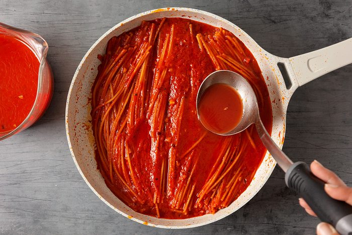 Add in a splash of tomato broth to just cover the top of the pasta; Bring to a simmer; reduce heat to medium