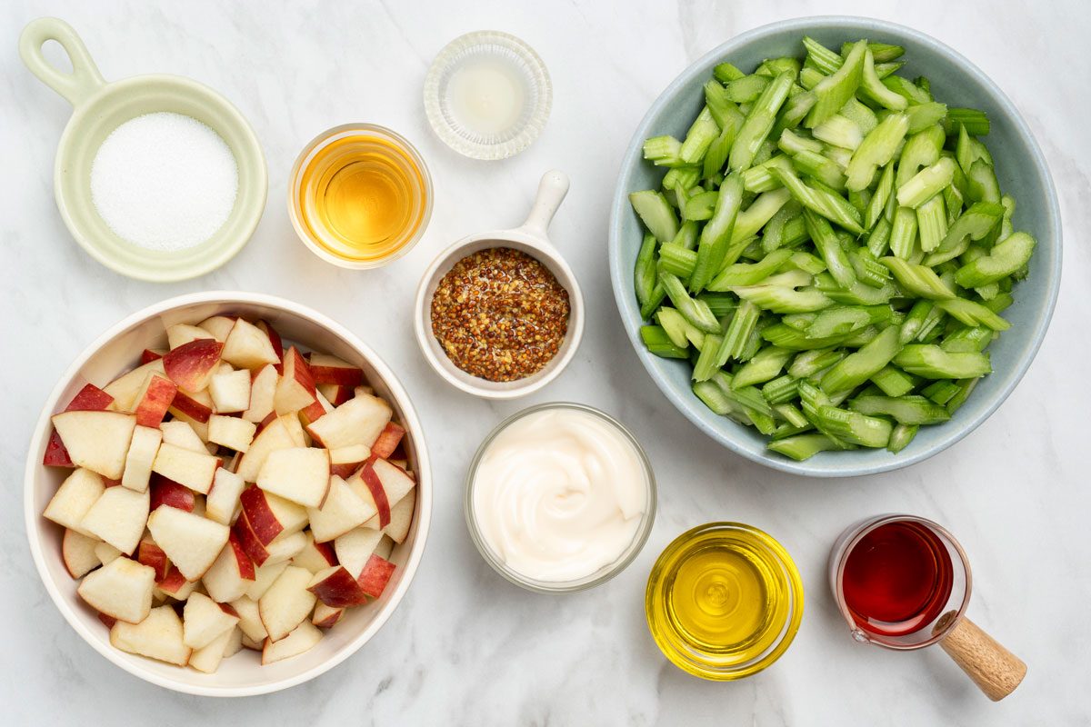 Overhead shot of all ingredients for Apple And Celery Salad arranged on a marble surface;