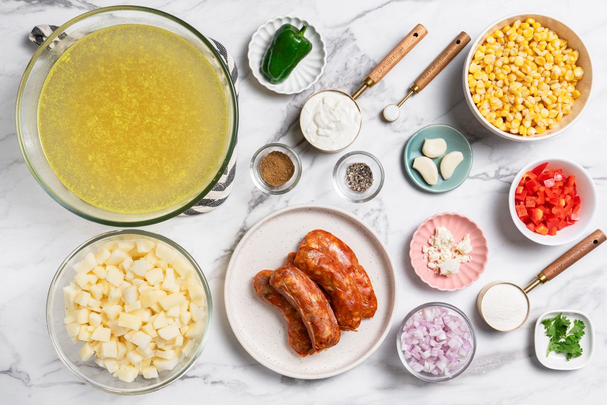 Overhead shot of all ingredients for Chorizo Soup arranged on a marble surface;