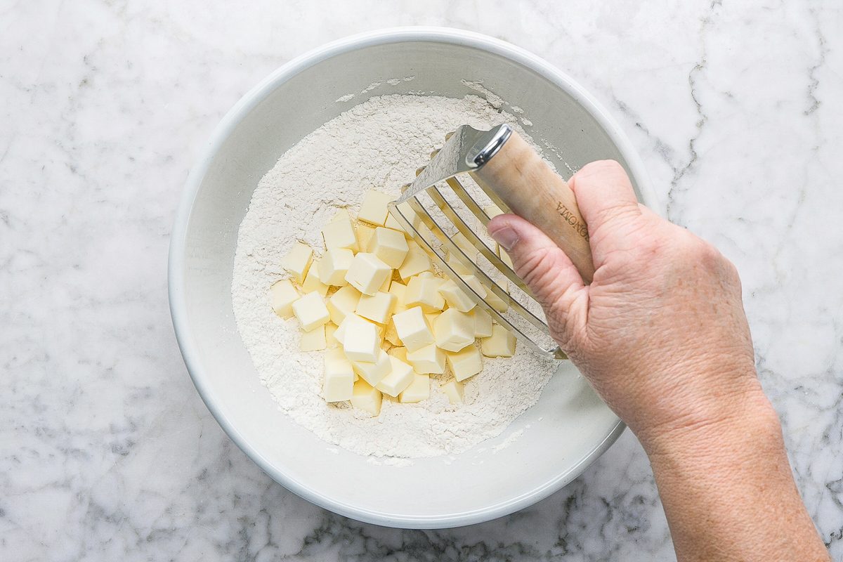 using a pastry blender to cut cold butter into the flour