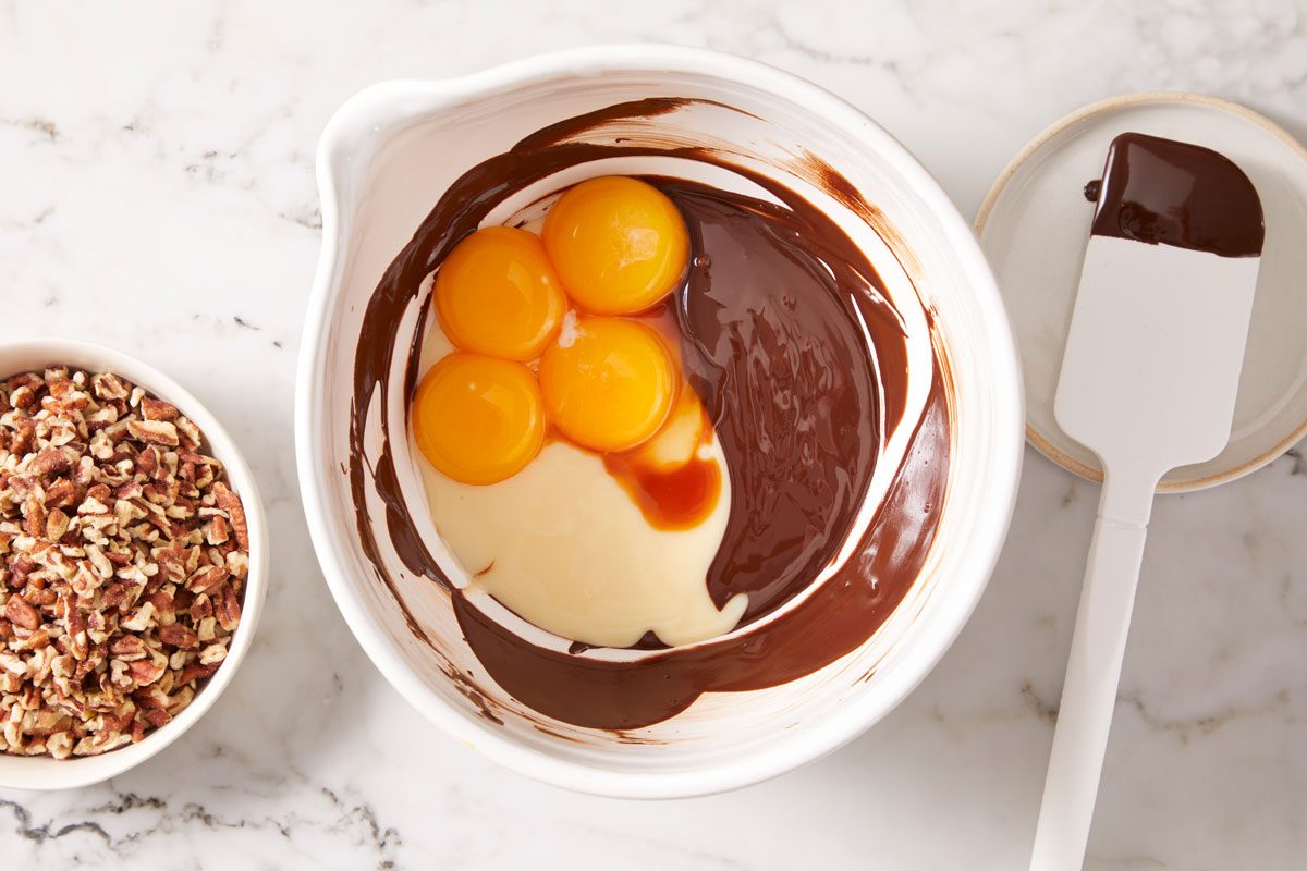 melt chocolate in a large bowl; stir until smooth.. Whisk in milk, egg yolks and vanilla;