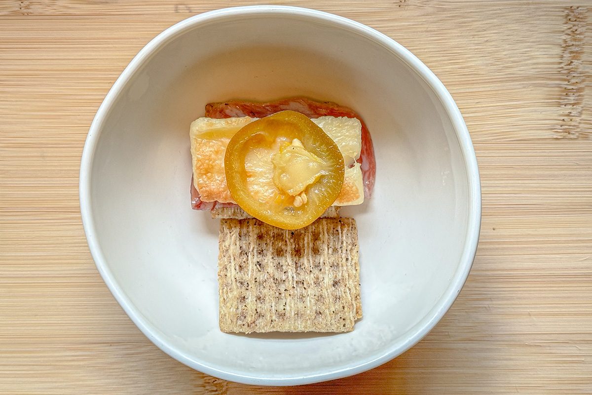 Hot Cheese layered in between crackers along with meat and spreads in a bowl