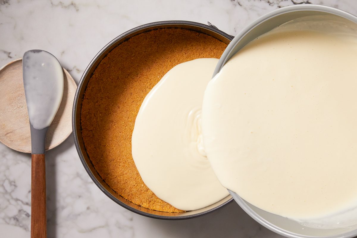 cheesecake filling being poured over crust