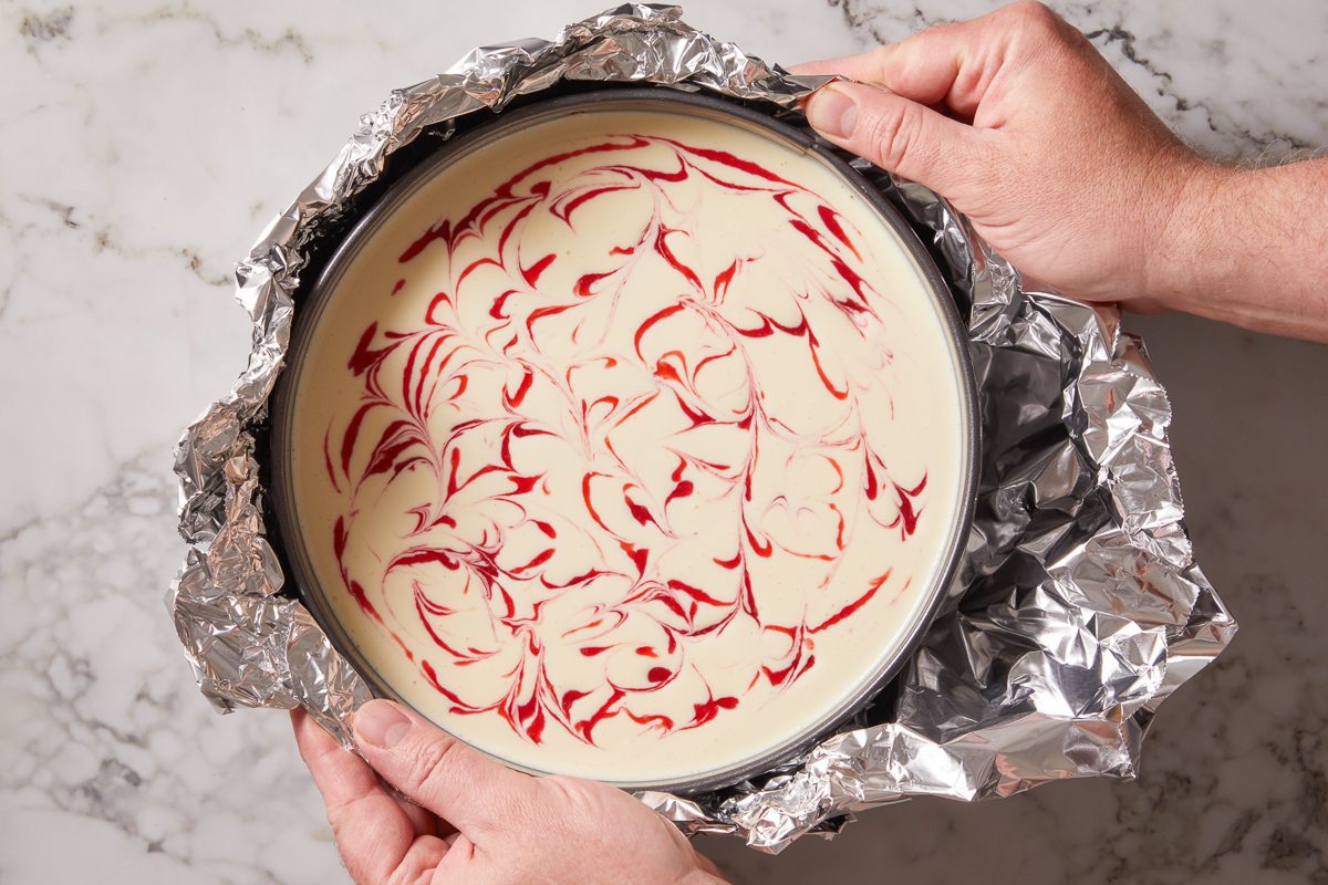 Placing the raspberry lemon cheesecake on a double thickness of heavy-duty foil