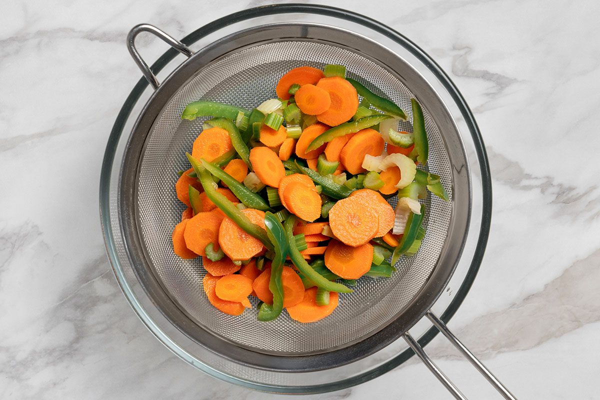 Boiled vegetable being drained in a large bowl