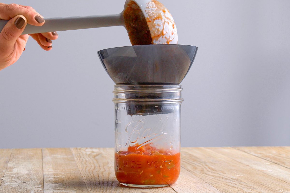salsa mix being poured in a mason jar with ladle