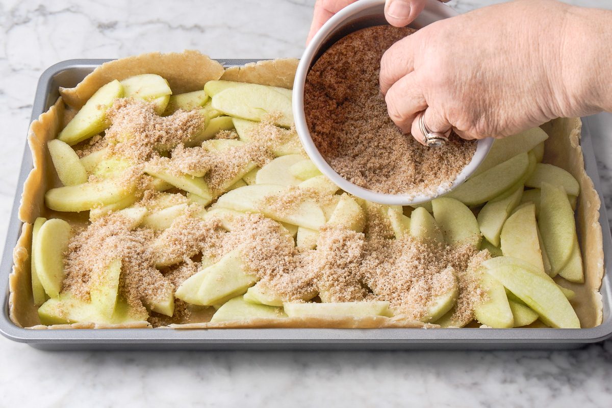 sprinkling sugars, cinnamon, nutmeg and salt mixture over apple slices