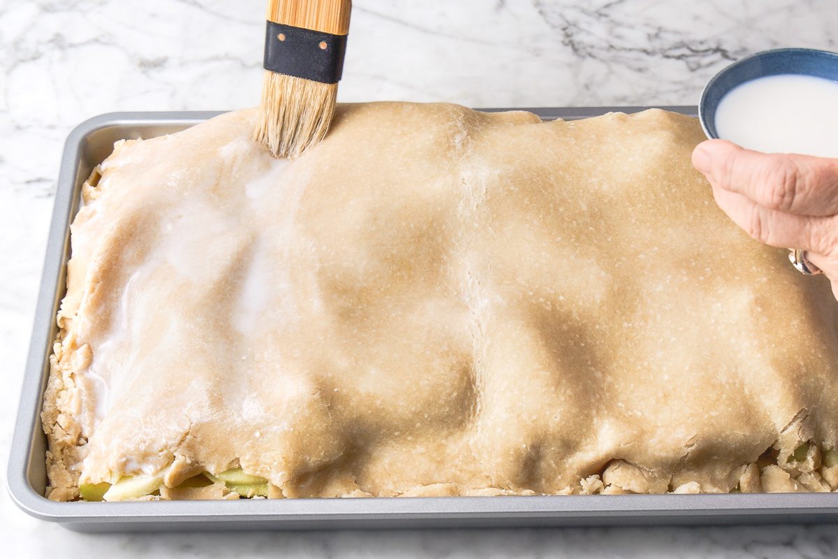 brushing top crust of pie with milk