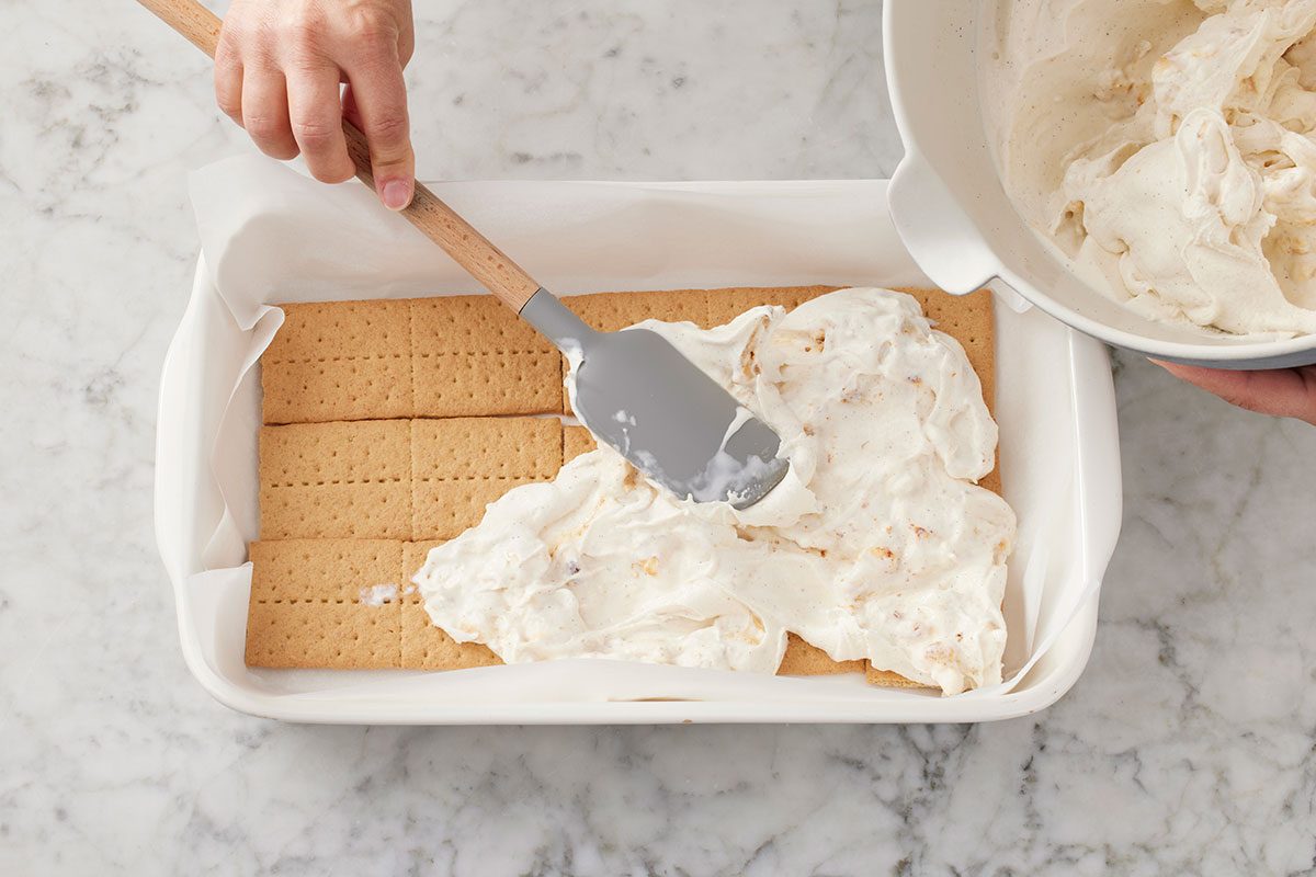 marshmallow-ice cream mixture being layered o the top of graham crackers