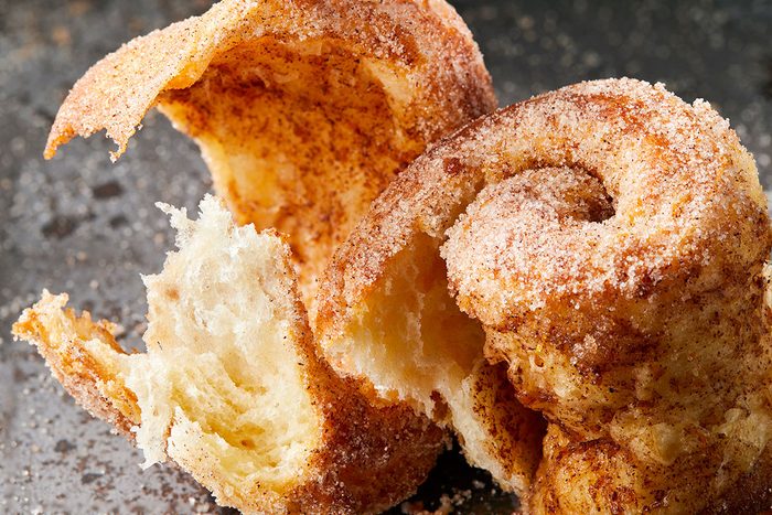Close-up shot of a Morning Buns torn open to reveal its soft; airy interior and golden; flaky layers dusted with cinnamon sugar.