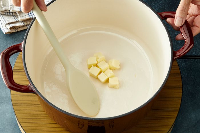 Overhead shot of a Dutch oven melt 2 tablespoons butter over medium heat; induction; dark surface;