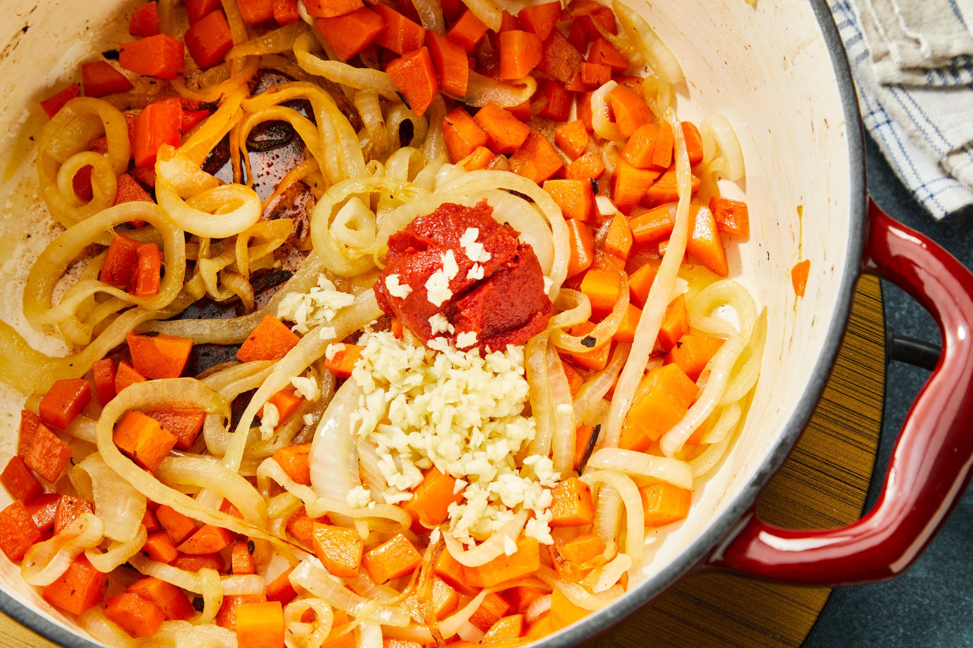 Close-up shot of add garlic and tomato paste; cook one minute longer; induction; napkin; dark surface;
