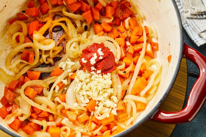 Close-up shot of add garlic and tomato paste; cook one minute longer; induction; napkin; dark surface;