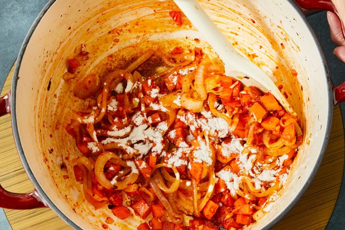 Overhead shot of stir in flour; cook until brown 2-3 minutes; induction; dark surface;