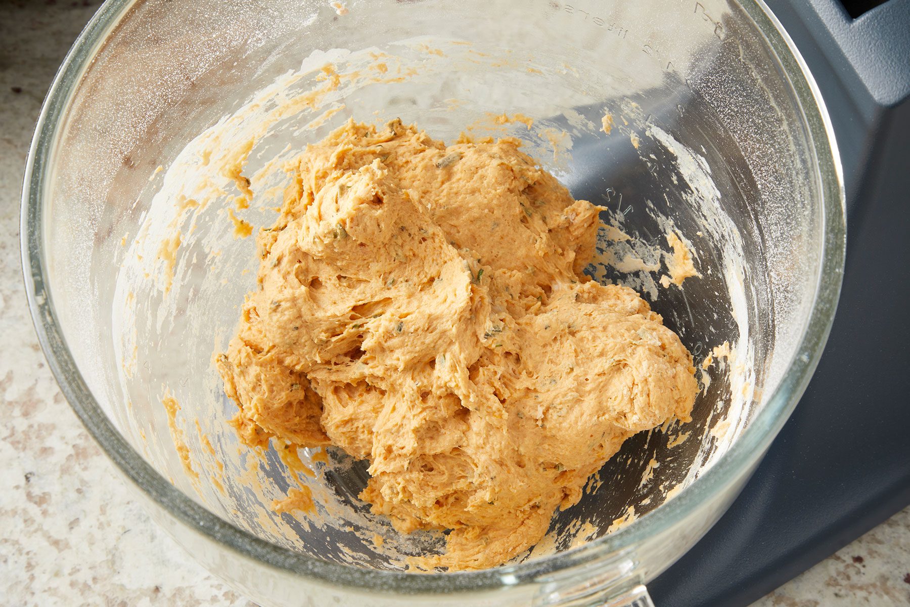 Sticky soft dough for Pumpkin Shaped Rolls in a glass bowl.