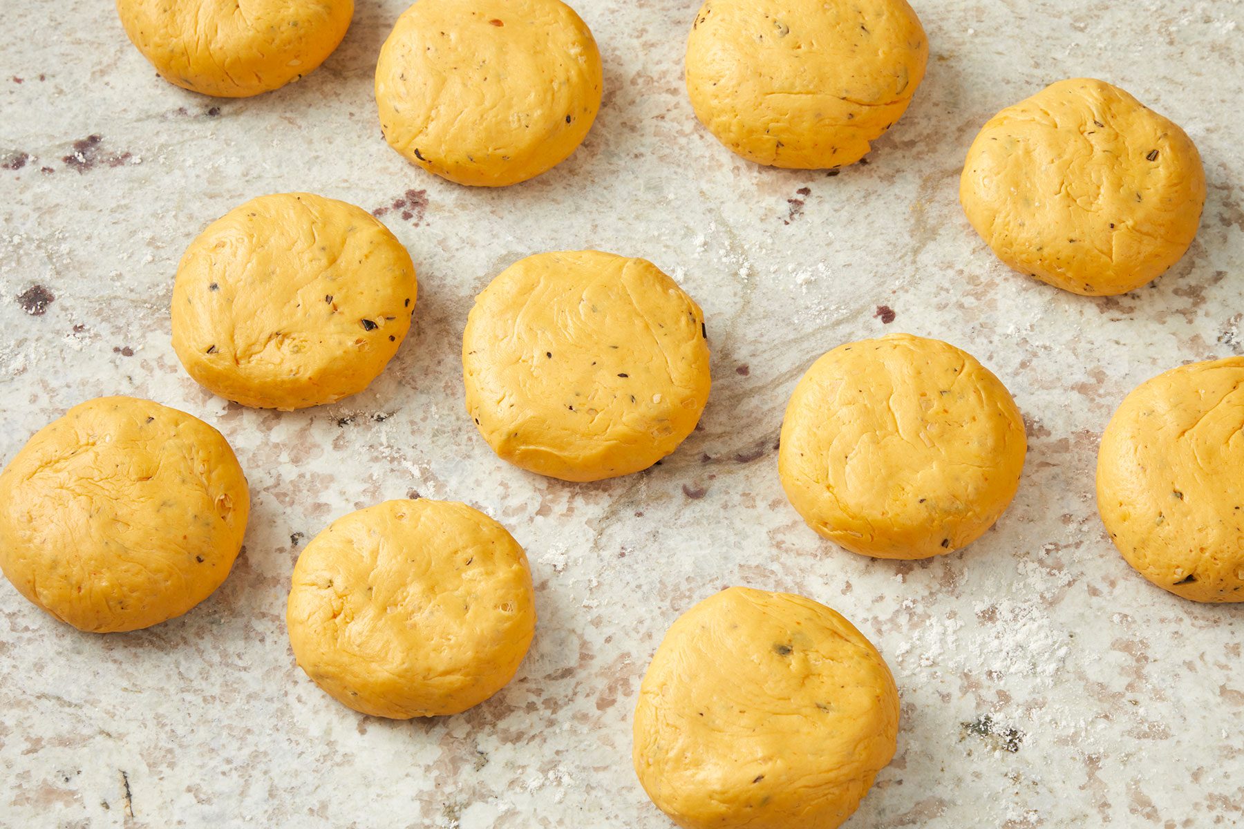 Flattened balls of dough equally divided in round shape and placed on counter.