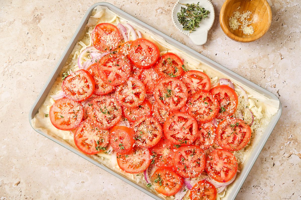 sliced onion and tomatoes arranged over the cheese