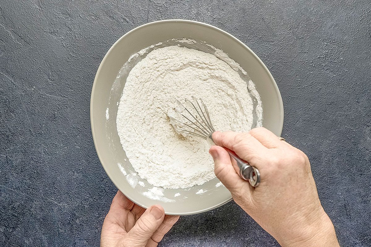 Overhead shot of combine the flour; baking powder and salt; gradually add to creamed mixture and mix well; dark surface