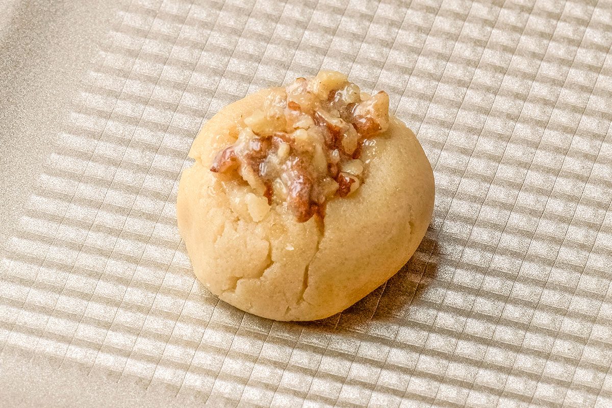 Close-up shot of spoon into indentations; Bake for 9-11 minutes or until lightly browned; baking sheet; dark surface