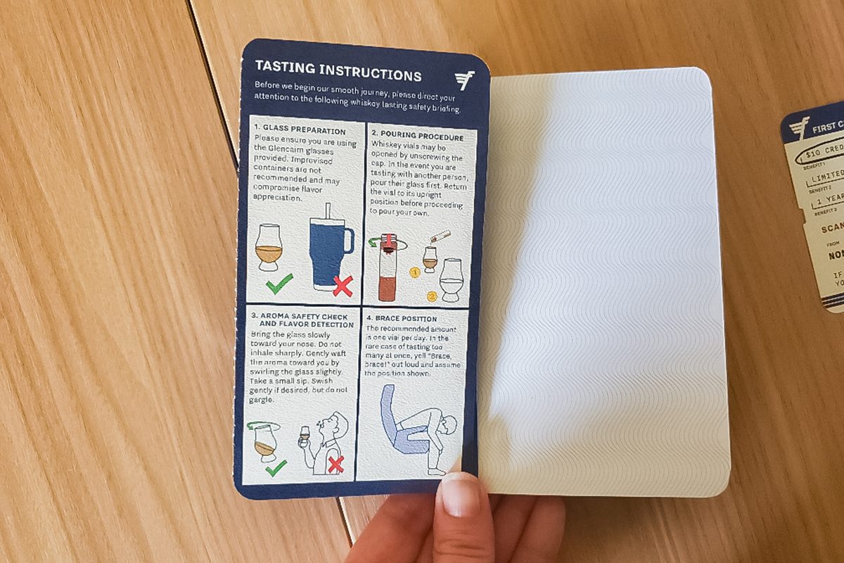 Person holding a booklet open to a page titled "Tasting Instructions" with illustrated steps and icons for tasting, cleaning glassware, and things to avoid, against a wooden surface background.
