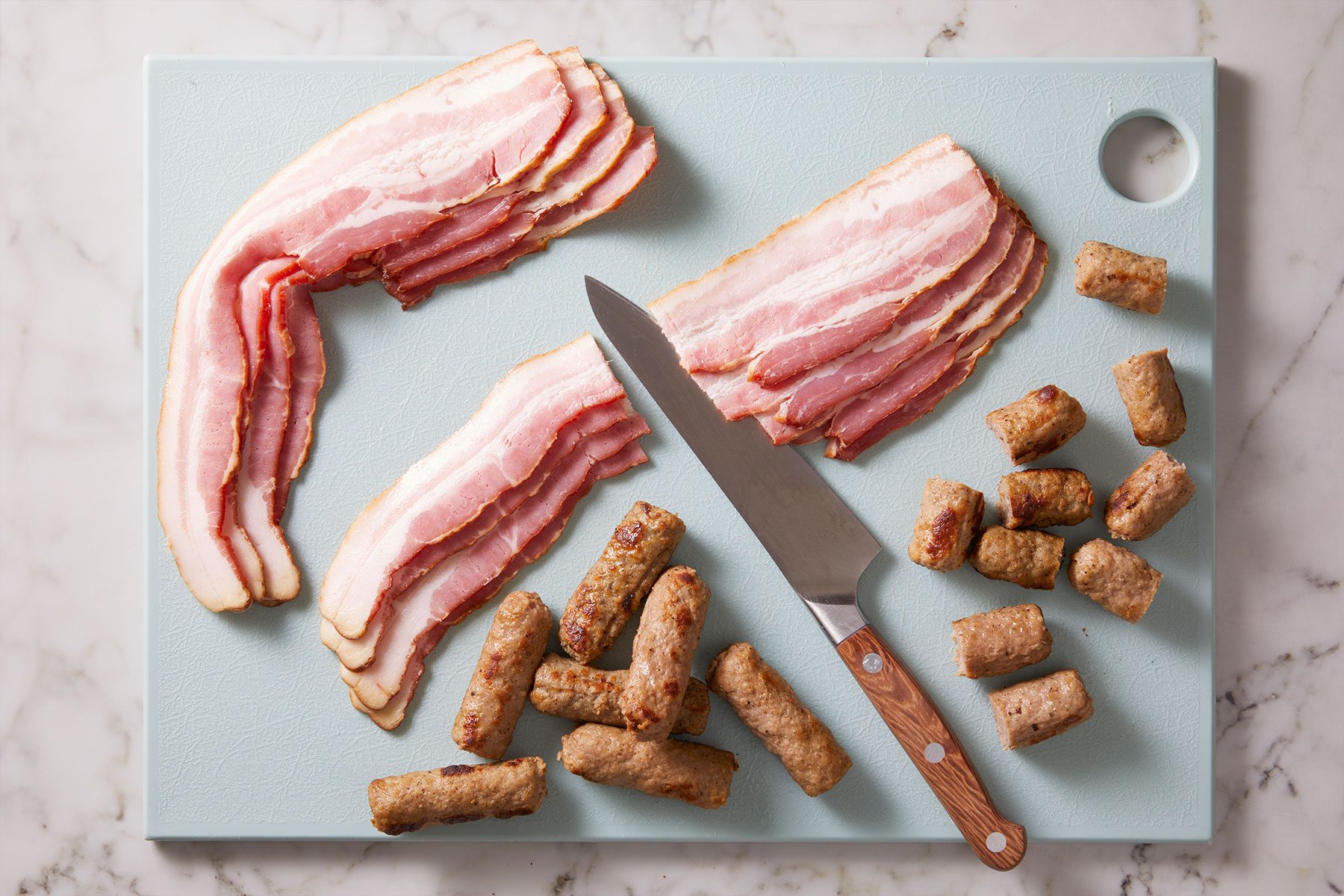 Bacon strips cut widthwise in half and cut the sausage links in half.