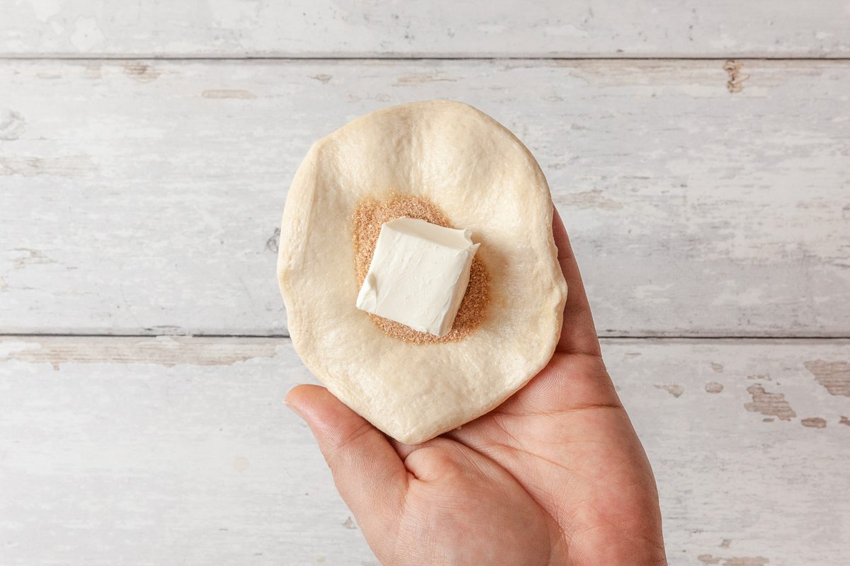 flattened biscuit topped with sugar cinnamon mixture and cube of cream cheese