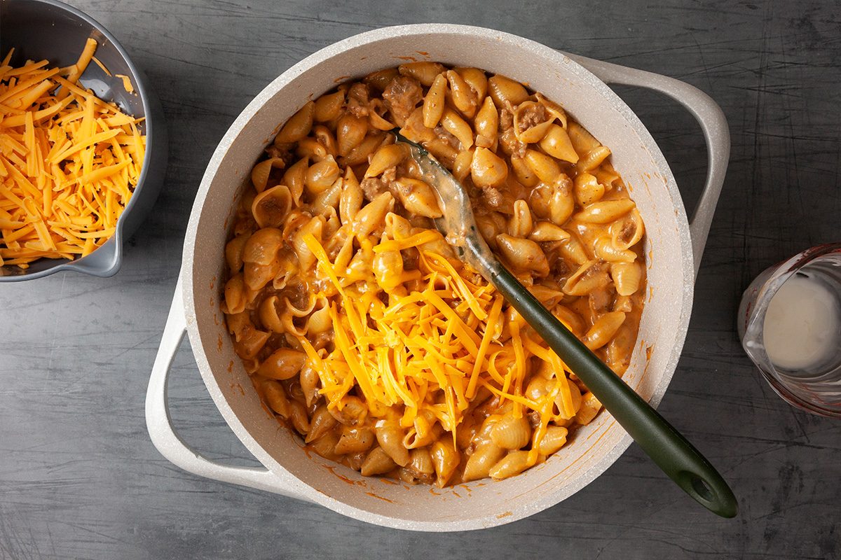 Overhead shot of a bowl of pasta topped with melted cheese and generous pieces of meat the sauce coats the noodles and everything looks savory