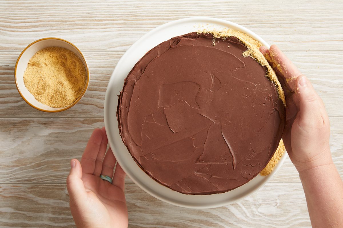 coating sides of the cake with crushed graham crackers