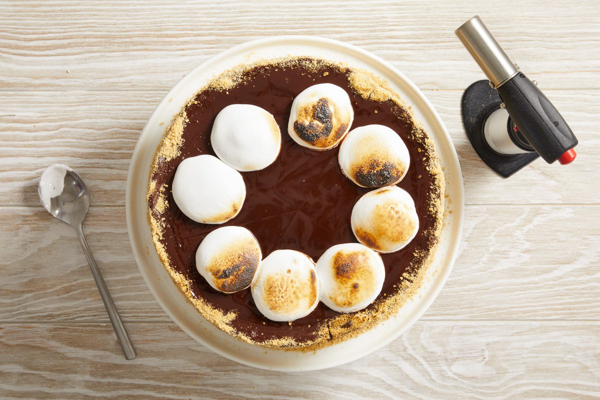 cake with torched marshmallow creme on top with kitchen torch next to it