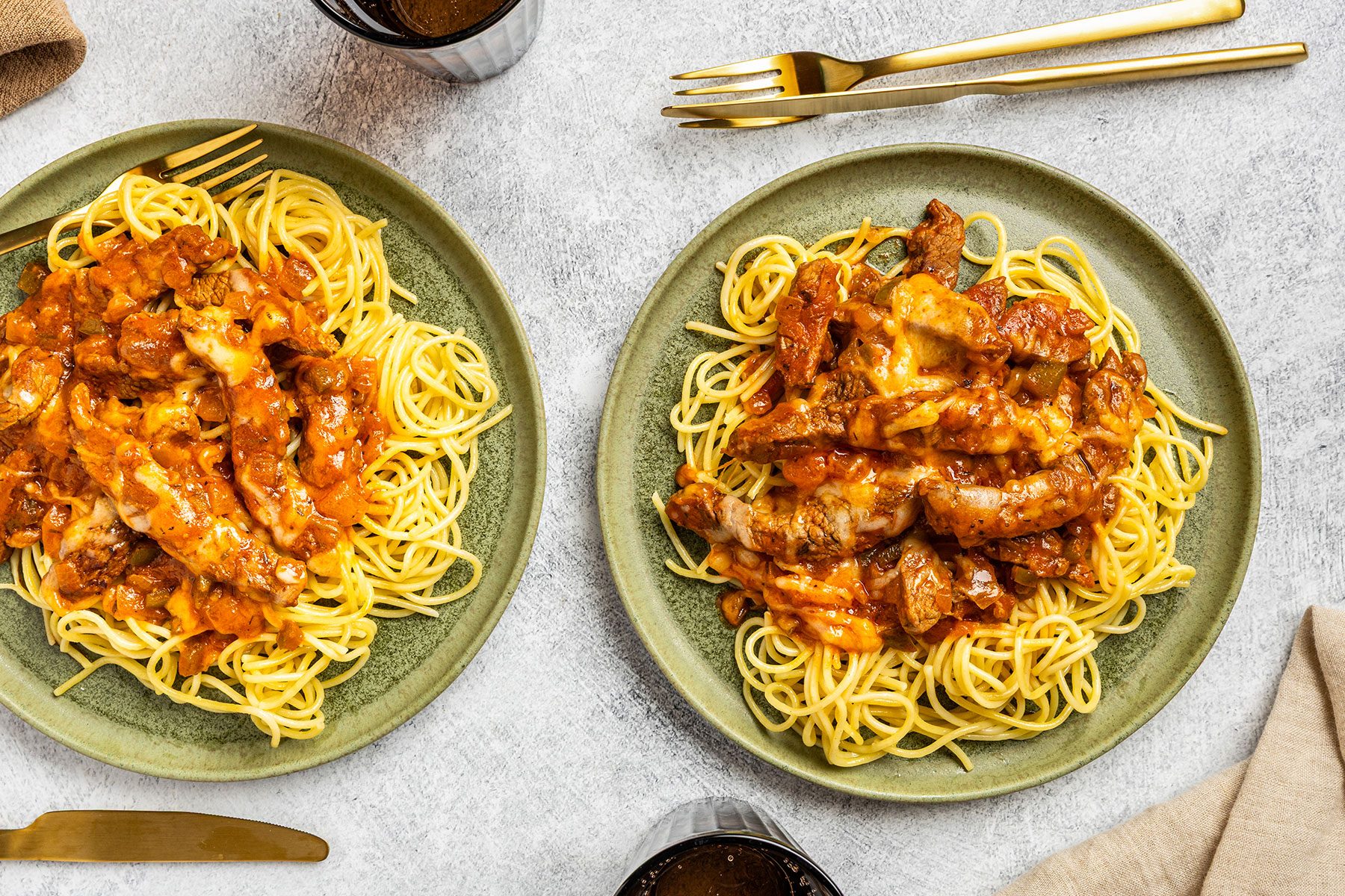 Steak And Spaghetti in two plates with forks kept on side.