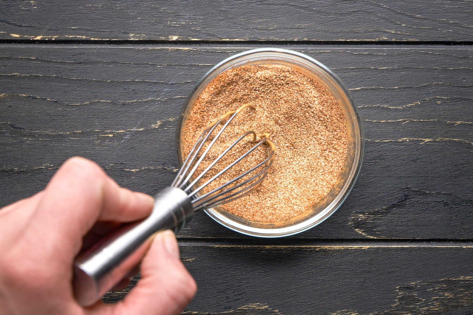 Stirring together the granulated sugar and cinnamon using a whisker in a bowl.