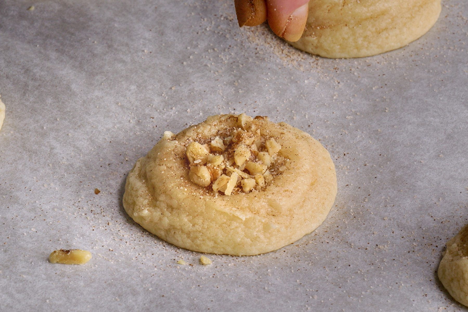 Sprinkling cinnamon sugar on a cookie with honey and walnuts.