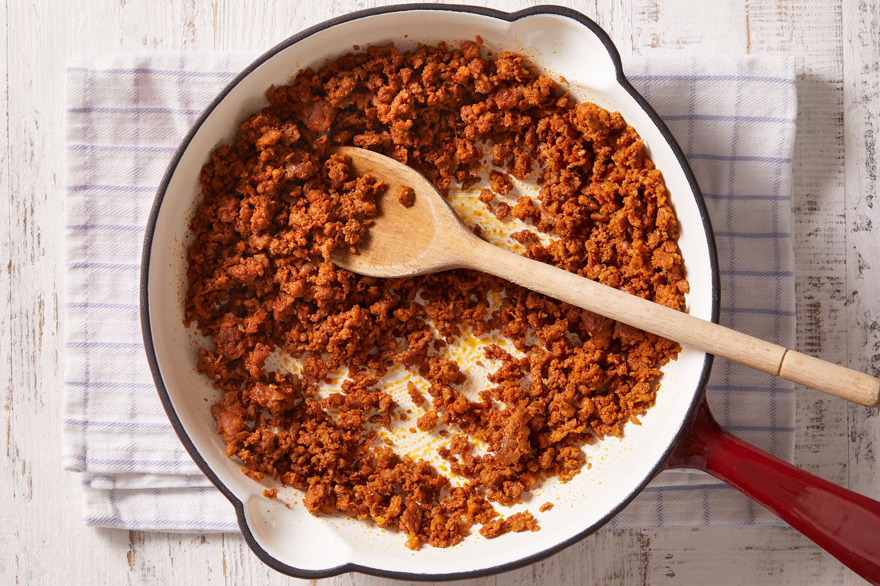 Cooking sausage over medium heat until it is cooked through, breaking it into crumbles with a spoon as it cooks in a heavy skillet.