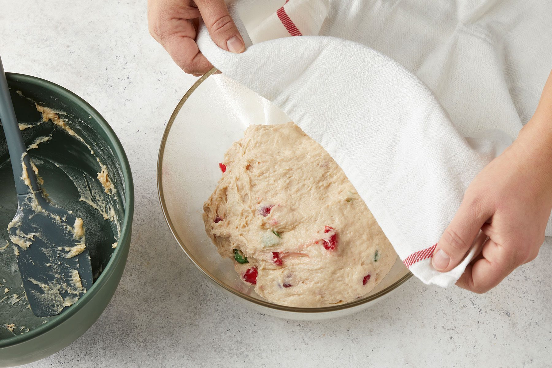 Placing dough in a greased bowl and covering the bowl with a clean kitchen towel.