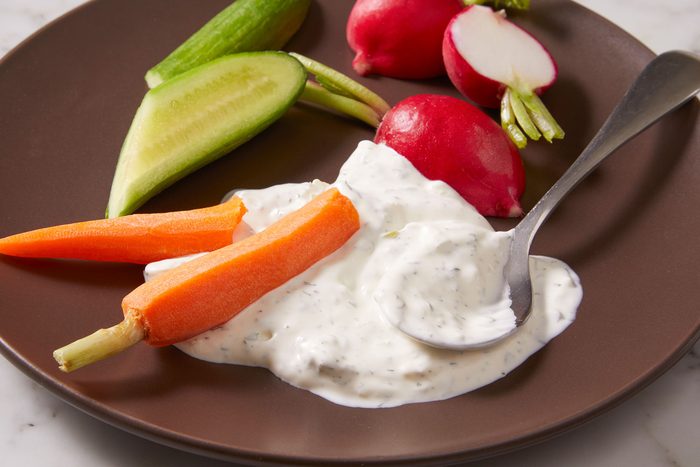 Crudite Dip in a plate with a lot of raw vegetables around it.